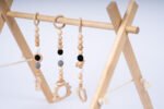 Дървена бебешка гимнастика Leg&Go с висящи сензорни играчки. Стимулира зрението, моториката и любопитството на бебето. Подходяща за игра от първите месеци.