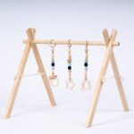 Стилна бебешка гимнастика Leg&Go от естествено дърво с три висящи сензорни играчки в меки сини и неутрални тонове. Насърчава зрителното възприятие, двигателната активност и любопитството на бебето още от първите месеци.