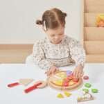 Дете играе с дървена пица VIGA Toys и приготвя храна в детска пицария